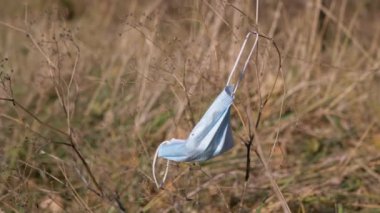 Ormandaki Kuru Ağaç Dalı 'nda kullanılmış tıbbi maske sallanıyor. 4K