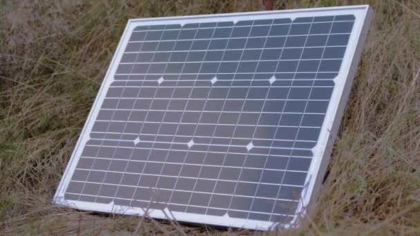 Jeden przenośny mały fotowoltaiczny panel słoneczny zainstalowany w trawie. Powiększenie — Wideo stockowe