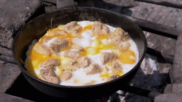 肉の準備は、たき火の上にフライパンで卵をスクランブルエッグ.4K — ストック動画