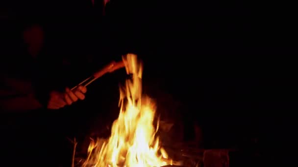 Homme mains friture deux saucisses juteuses la nuit sur un feu de joie en plein air dans la forêt — Video