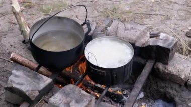 Açık havada, ormanda bir tencerede şenlik ateşinde yemek hazırlıyorum. 4 bin. Kapat.