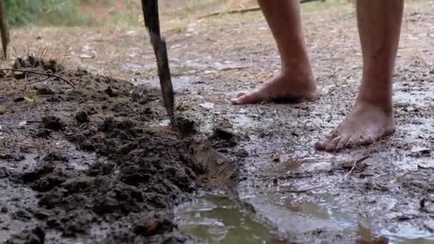 Human Digs a Storm Drain, a Trench, a Drainage in Wet Earth com o uso de uma pá — Vídeo de Stock