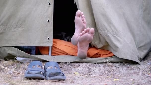 Bare Feet Man Legs kikar ut från ett öppet militärt tält i naturen. Närbild — Stockvideo