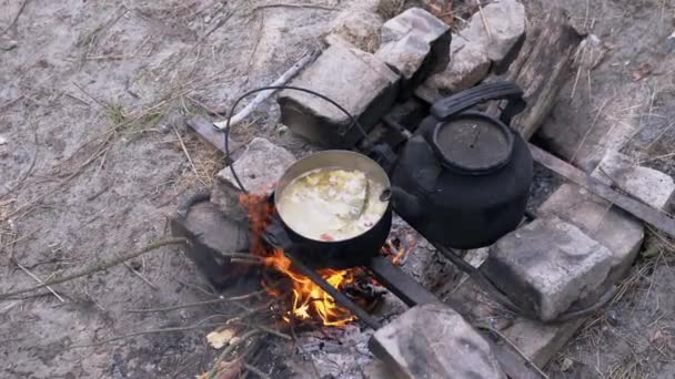 Maschio Preparare il cibo in una casseruola su un falò in boschi all'aperto. 4K. Da vicino. — Video Stock