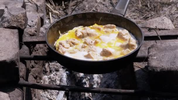 Préparation des œufs brouillés de viande dans une poêle sur le feu de joie. Zoom — Video