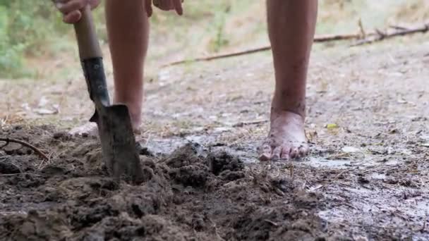 Människan gräver en storm avlopp, en grav, en dränering i våt jord med hjälp av en skyffel — Stockvideo
