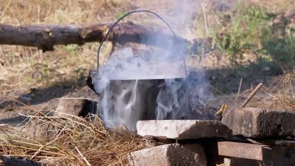 Cucinare il cibo in una casseruola Durante un falò aperto nel fumo al tramonto. Zoom — Video Stock