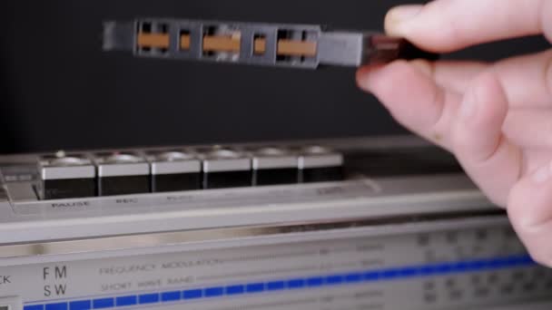 Mano masculina pone un viejo casete de audio en los botones de una grabadora de cinta vintage — Vídeos de Stock