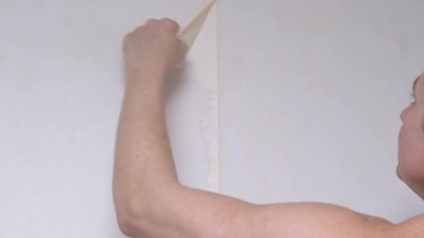 Männlich entfernt alte Papiertapeten an der Wand. 4K. Nahaufnahme — Stockvideo