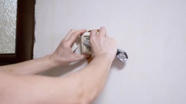Bir erkek elektrikçi duvarda eski bir şalteri rahibin bıçağıyla söktü.