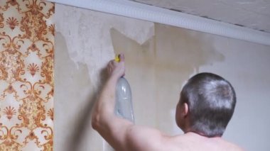 Erkek El, eski duvar kağıdını duvardan kaldırmak için sprey şişeden su püskürtür. 4K