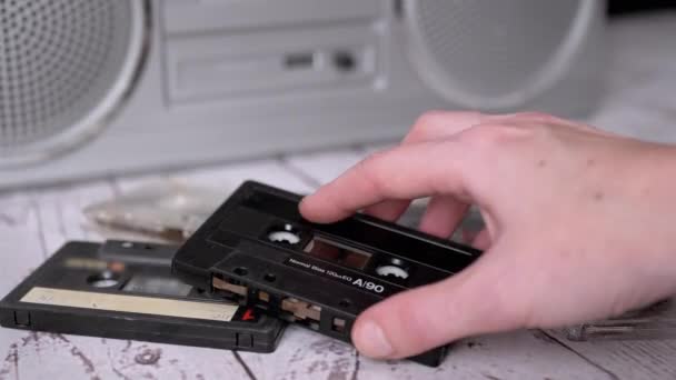 Žena ruka zvedne jednu starou hudební kazetu z 90. let od stolu — Stock video