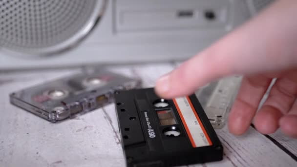 Mano femenina recoge un casete de audio de música antigua de los años 90 de la mesa — Vídeo de stock