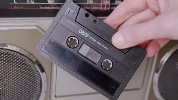 Rotación de mano femenina un casete de audio antiguo de los 90 cerca de una grabadora de cinta estéreo — Vídeo de stock
