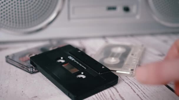 Mano femenina recoge un casete de audio de música antigua de los años 90 de la mesa — Vídeo de stock