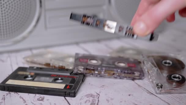 Female Hand zet een oude klassieke zwarte audiocassette op de tafel. 4K. Sluiten. — Stockvideo