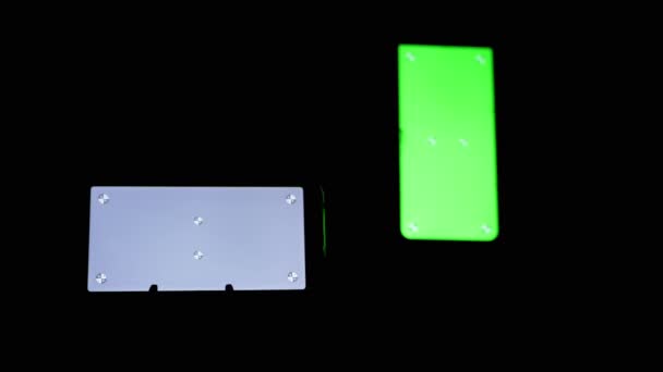 Twee smartphones met een groen, grijs scherm, chroma, markeringen op een zwarte achtergrond — Stockvideo
