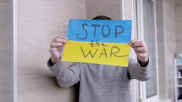 Dziecko trzyma w rękach plakat z flagą Ukrainy, i wiadomość zatrzymać wojnę — Wideo stockowe