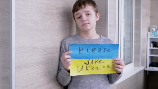 Niño sostiene una pancarta con una bandera azul y amarilla, Mensaje Por favor, salve Ucrania — Vídeo de stock