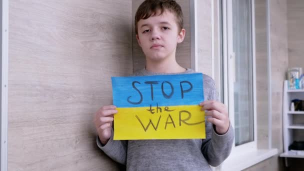 Niño sostiene en las manos un cartel con una bandera de Ucrania, y el mensaje Alto a la guerra — Vídeos de Stock