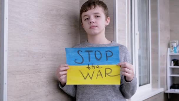 Dziecko trzyma w rękach plakat z flagą Ukrainy, i wiadomość zatrzymać wojnę — Wideo stockowe