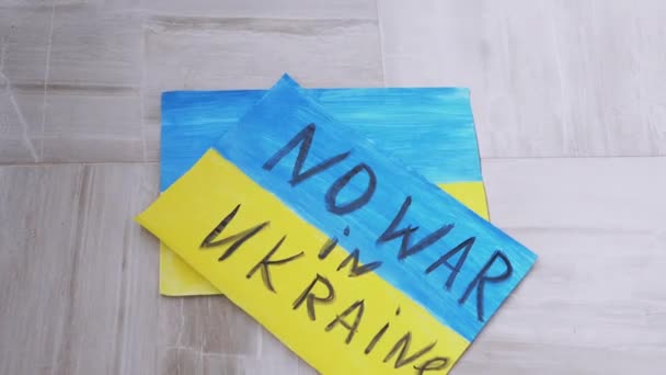 Жіночі руки викладають малюнки на підлозі з написами "Зупиніть війну в Україні" — стокове відео