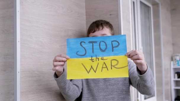 Niño sostiene en las manos un cartel con una bandera de Ucrania, y el mensaje Alto a la guerra — Vídeos de Stock