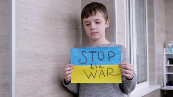 Kind houdt in handen een poster met een vlag van Oekraïne, en bericht Stop de oorlog — Stockvideo