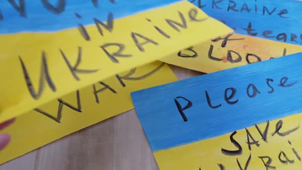 Жіночі руки викладають малюнки на підлозі з написами "Зупиніть війну в Україні" — стокове відео