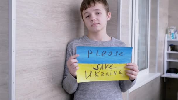 Ребенок держит знамя с голубым и желтым флагом, сообщение Пожалуйста, спасите Украину — стоковое видео