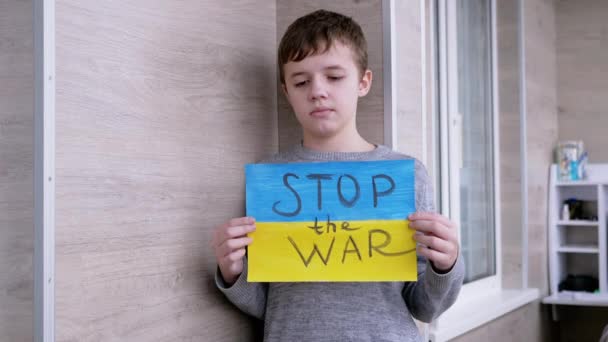 Ребенок держит в руках плакат с флагом Украины и послание "Остановить войну" — стоковое видео