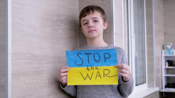 Ребенок держит в руках плакат с флагом Украины и послание "Остановить войну" — стоковое видео