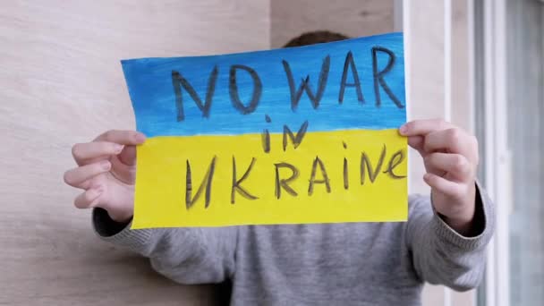 Niño sostiene en las manos una pancarta con una bandera de Ucrania, y Mensaje No Guerra — Vídeos de Stock