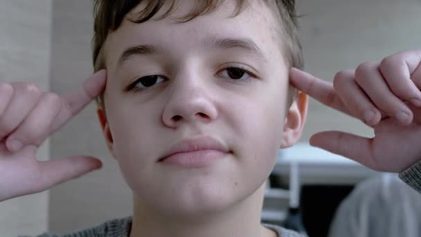 Portrait of a Disgruntled Child who Twists his Finger to Temple. Close up. 4K — Stock Video