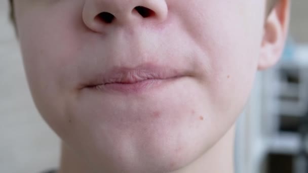 Divertido retrato de la cara de un niño sonriente lamiéndose los labios. Primer plano — Vídeos de Stock