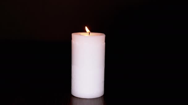 一个黑色背景上的白色大燃烧蜡烛。前景 — 图库视频影像