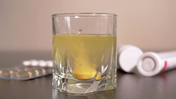 Tableta efervescente cayendo en un vaso de agua sobre el fondo de los medicamentos — Vídeo de stock