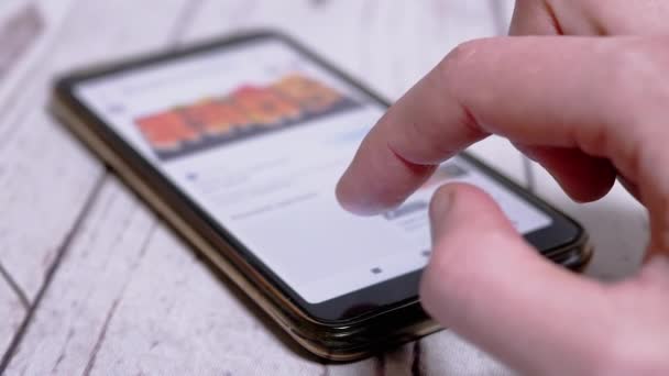 Kvinna är Bläddrar på Internet-menyn i en smartphone för att beställa sushi hemma — Stockvideo