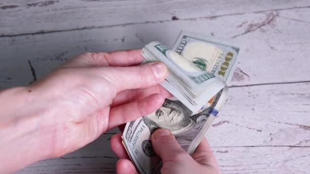 As mãos femininas estão contando uma pilha de notas de 100 dólares, folheando através de notas — Vídeo de Stock