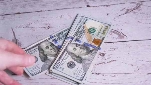 Vrouwelijke handen gooien een stapel van 100 dollar rekeningen op de tafel. Zoom uit. Sluiten. — Stockvideo