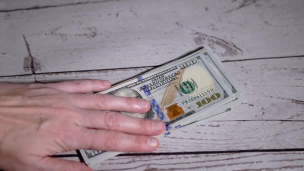 "Руки женщины выкладывают стопку банкнот по 100 долларов, считая деньги". Медленное движение — стоковое видео