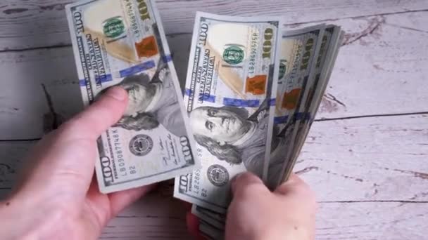 As mãos femininas estão contando uma pilha de notas de 100 dólares, folheando através de notas — Vídeo de Stock