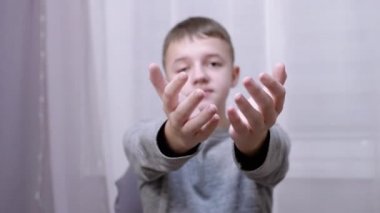 Gülümseyen, gülümseyen, elini ileri uzatırken öpüşen beyaz çocuk.