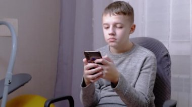Çocuk sandalyeye oturur, elinde akıllı telefon tutar, mesajını Chat 'te yazar. Kapat.