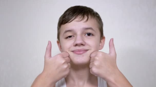 Rapaz positivo segurando polegares na frente da câmera, mostrando um sinal de consentimento — Vídeo de Stock
