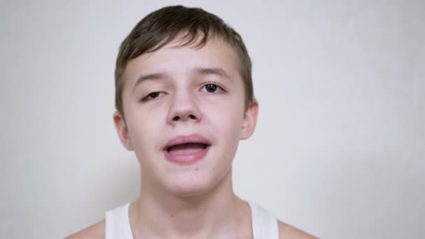 Smiling Teenager Gesticulates with Mouth, Showing his Teeth, Tongue. De cerca. — Vídeo de stock