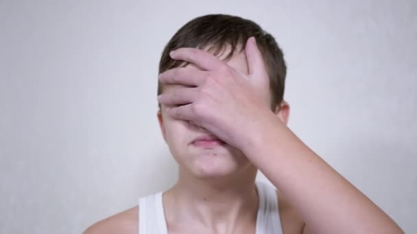 Turhautunut lapsi iskee itsensä kasvoihin kämmenellä. 4K. Sulje se. Hidastus — kuvapankkivideo