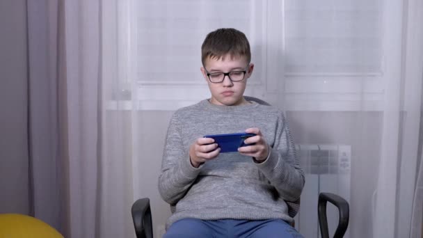 Удивленный ребенок в очках, смотрящий видео в мобильном приложении на смартфоне — стоковое видео
