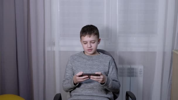 Menino bonito conversando em um smartphone on-line no quarto — Vídeo de Stock