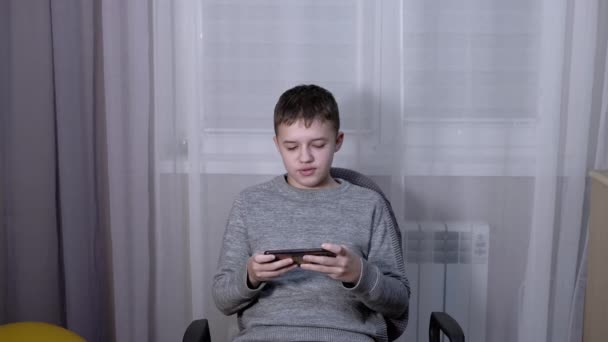 Beau garçon parler sur un smartphone en ligne dans la chambre. — Video
